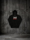 Hoodie Taxé mais encore en vie noir, face, sur mur béton