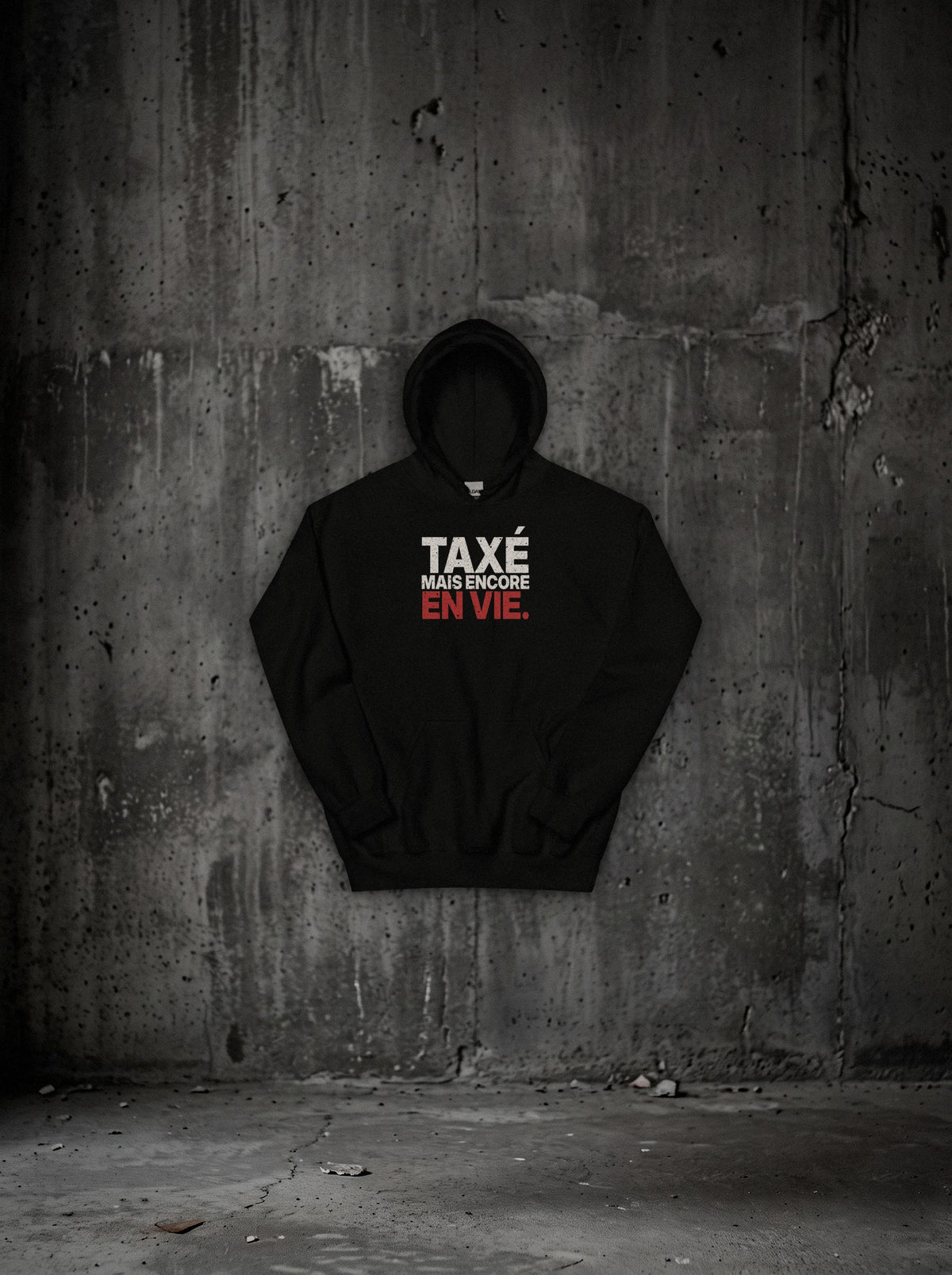 Hoodie Taxé mais encore en vie noir, face, sur mur béton