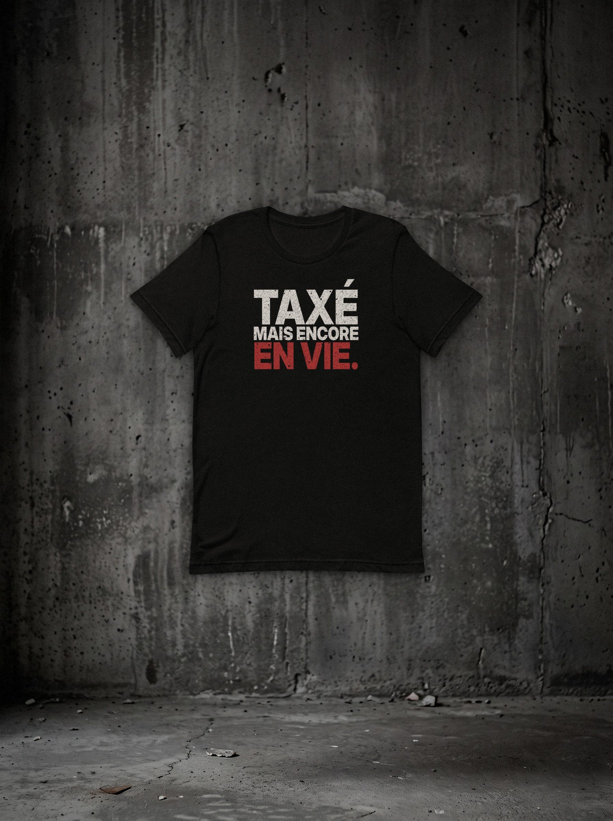 T-shirt « TAXÉ MAIS ENCORE EN VIE. » SURVIVORRR, vue face sur mur béton